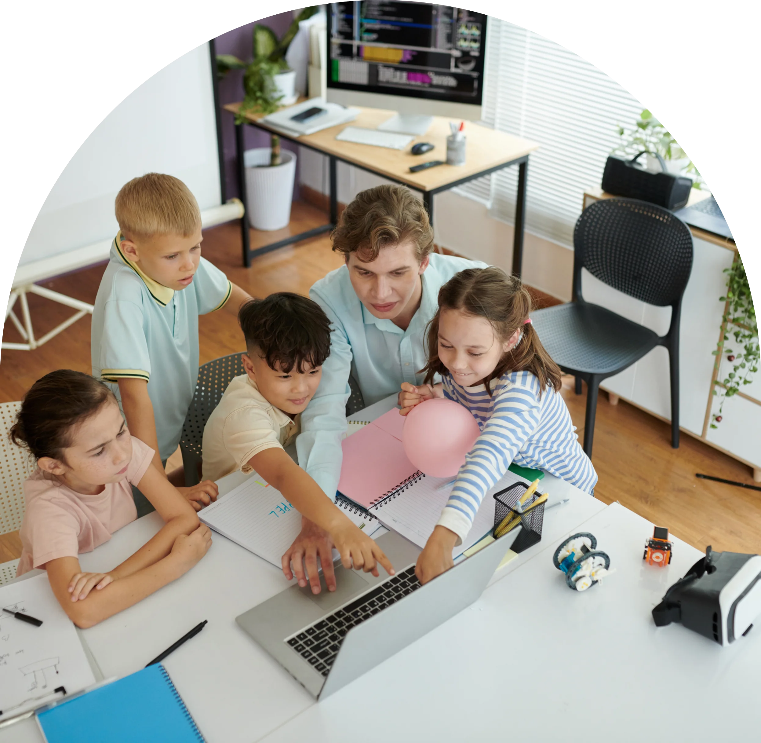 GettyImages-2192762322 (5) Children and teacher gathered around a laptop.