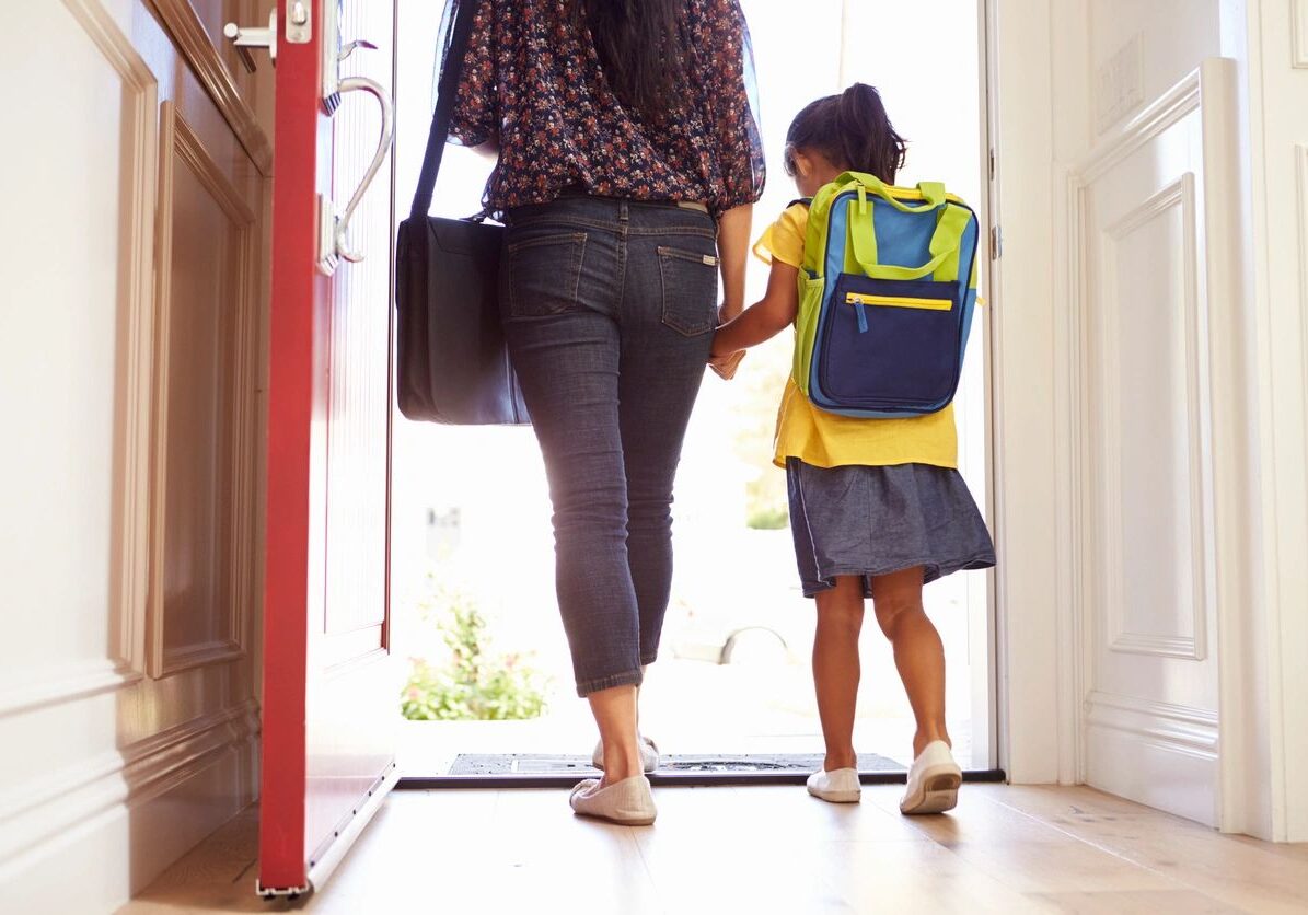 A woman and child walking in front of a door.